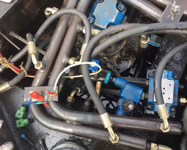Close-up of polished hydraulic hoses, valves and metal fittings arranged on industrial equipment, deep blue and steel gray tones with bright highlights.